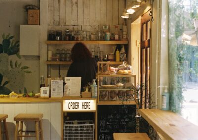 A cozy coffee shop with a counter and order sign, showcasing pastries and beverages.