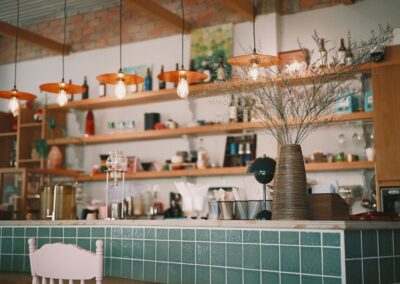 A stylish coffee shop interior featuring pendant lights and decorative vases on green tiled counter.