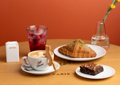 Elegant cafe setting with a cappuccino, croissant, brownie, and iced drink, perfect for a Parisian brunch vibe.