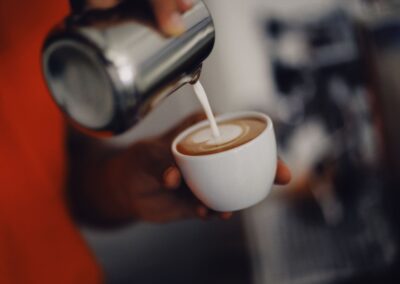 Close-up of a barista pouring steamed milk to create latte art in a coffee cup.